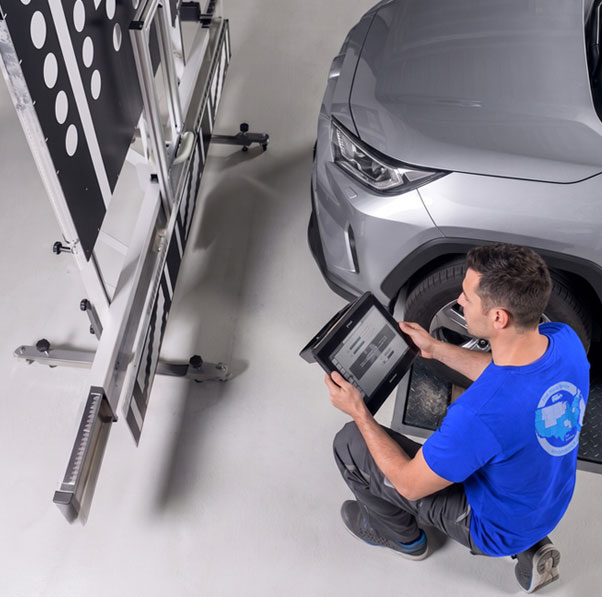 Technician setting up an ADAS calibration target frame beside a vehicle in Tampa