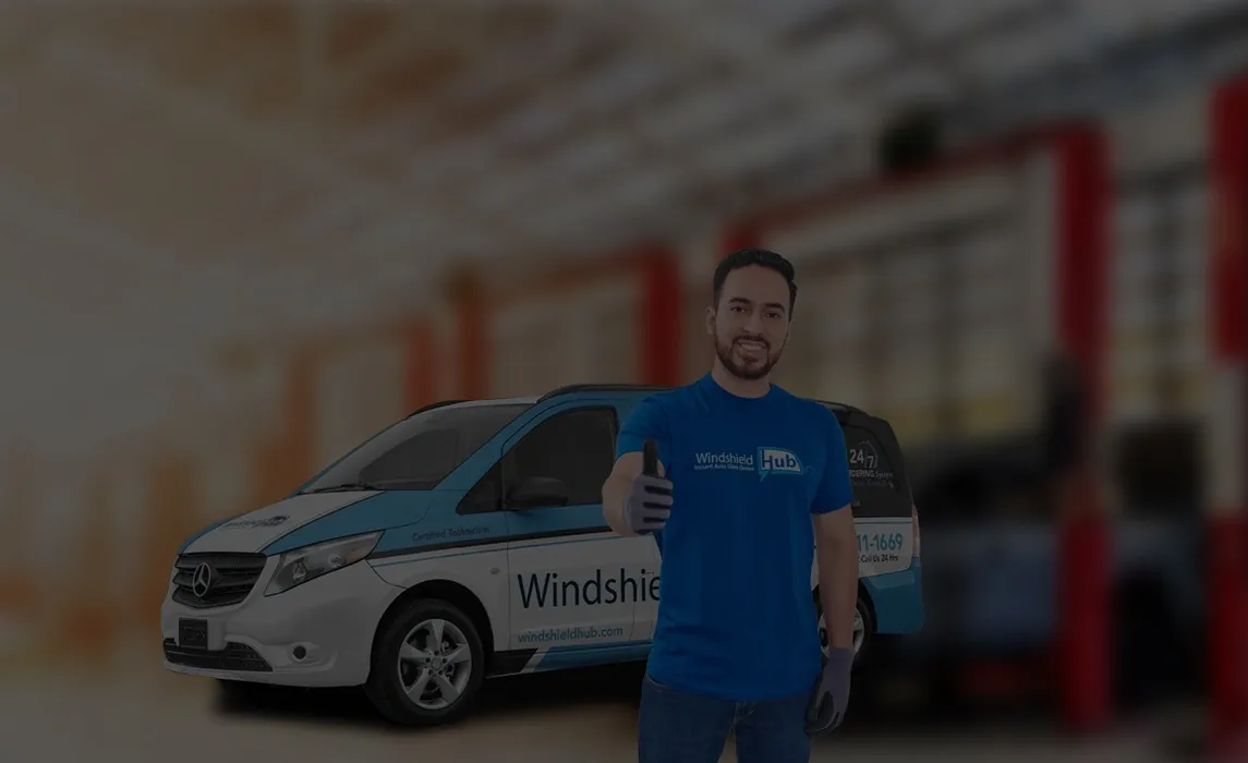 A person holds a large piece of windshield glass. Behind them is a white and blue van with Windshield Hub branding and text that reads Your Local Experts for Auto Glass