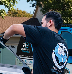 Technician installing a windshield at a customer's home with mobile auto glass service van in background