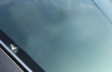Small chipped corner on lower windshield near driver side with visible impact mark